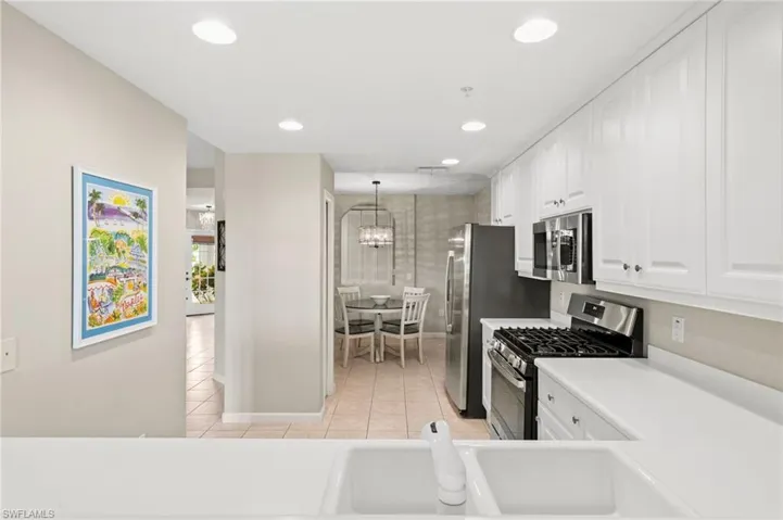 Kitchen with appliances with stainless steel finishes, white cabinets, decorative light fixtures, light countertops, and light tile patterned floors