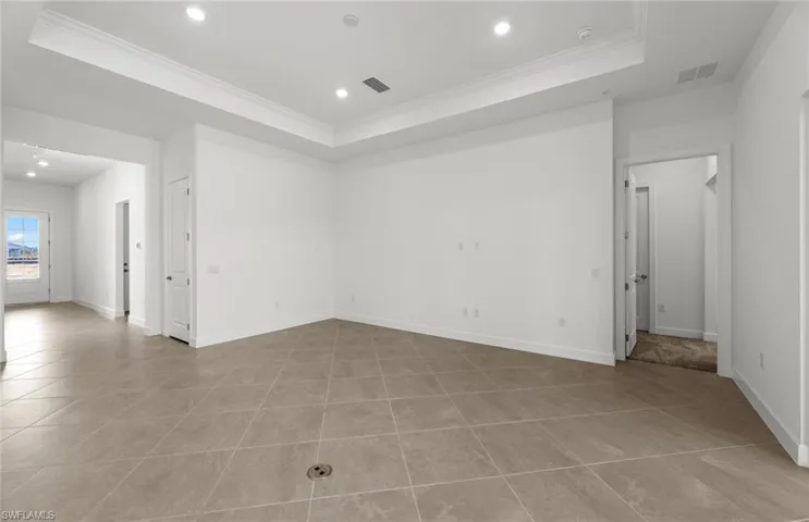 Tiled empty room with ornamental molding and a raised ceiling