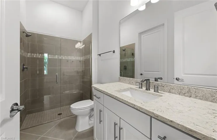 Bathroom featuring tile flooring, a shower with shower door, toilet, and vanity