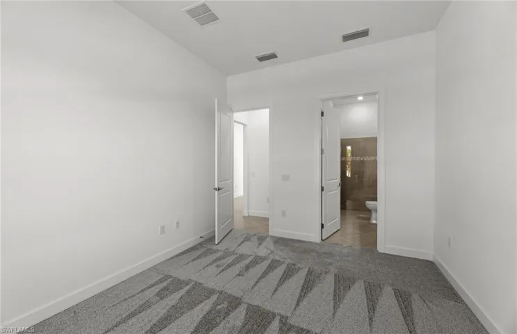 Unfurnished bedroom featuring carpet and ensuite bathroom
