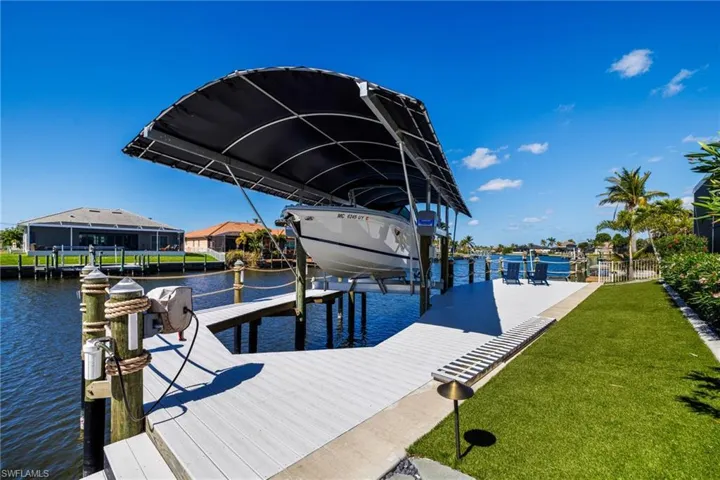 View of dock featuring a water view, boat lift, and a yard (turf)