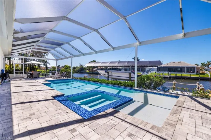 View of pool with integrated spa/hot tub, screen enclosure, overlooking the canal