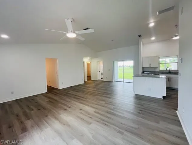 Unfurnished living room with recessed lighting, ceiling fan, high vaulted ceiling, and dark wood finished floors