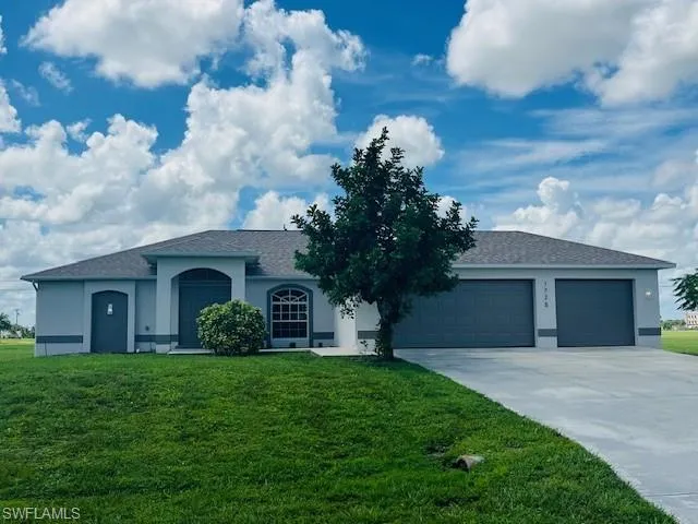 View of front facade featuring stucco siding, a front lawn, concrete driveway, a shingled roof, and a garage
