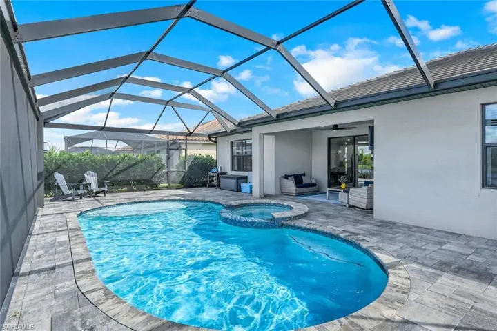 View of swimming pool featuring glass enclosure, ceiling fan, and a patio area