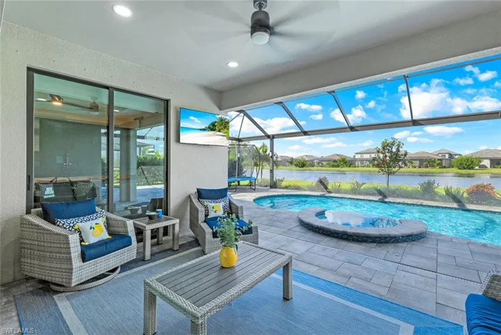 View of swimming pool with a lanai, ceiling fan, a patio area, and a jacuzzi