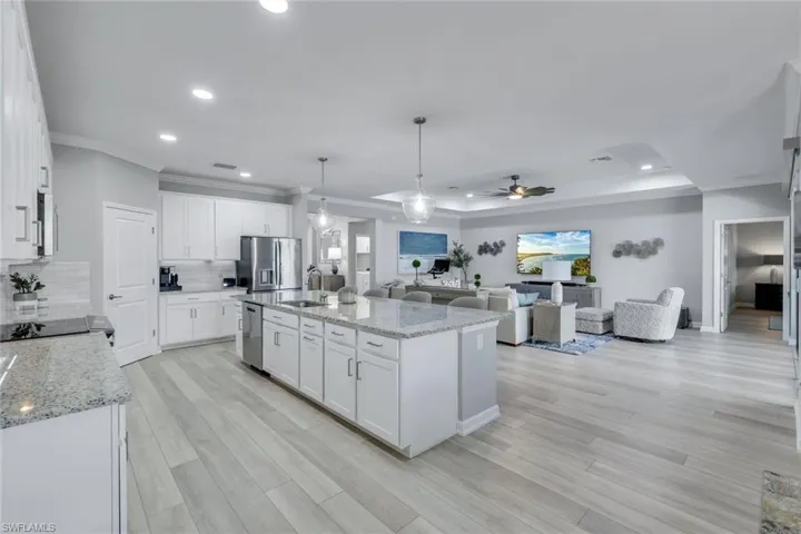 Kitchen featuring ceiling fan, sink, a center island with sink, white cabinetry, and stainless steel appliances