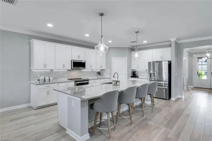 Kitchen featuring white cabinets, a kitchen island with sink, appliances with stainless steel finishes, and light hardwood / wood-style flooring