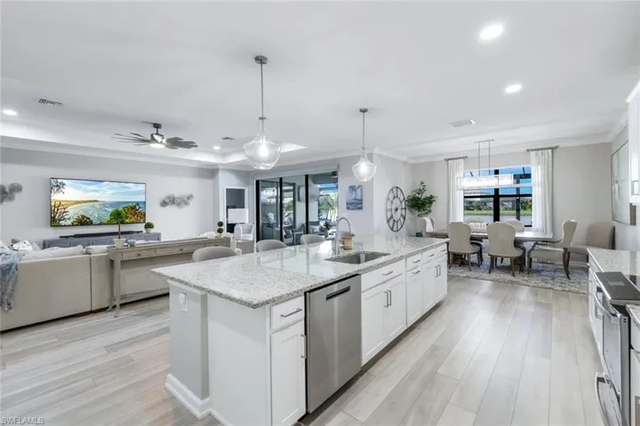 Kitchen featuring white cabinetry, stainless steel appliances, ceiling fan, a kitchen island with sink, and sink