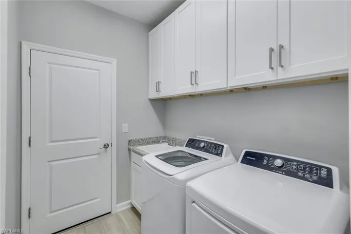 Laundry area featuring light hardwood / wood-style floors, sink, washing machine and clothes dryer, and cabinets