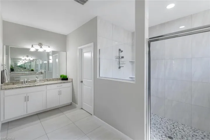 Bathroom with tile patterned floors, a shower with door, and vanity