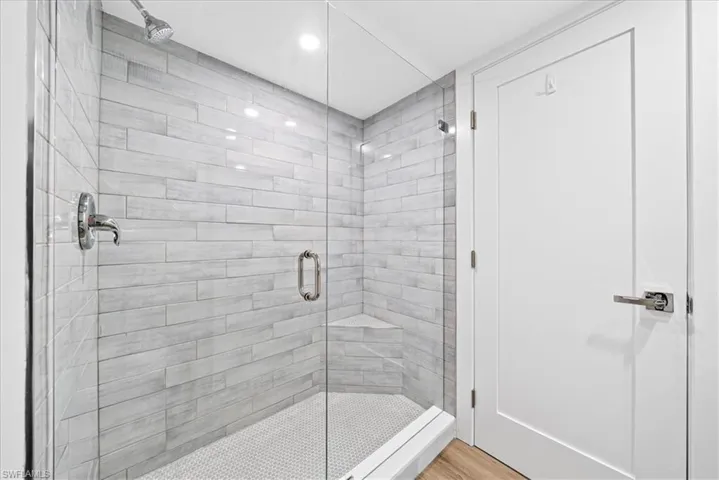 Full bath with a shower stall, recessed lighting, and light wood-style floors