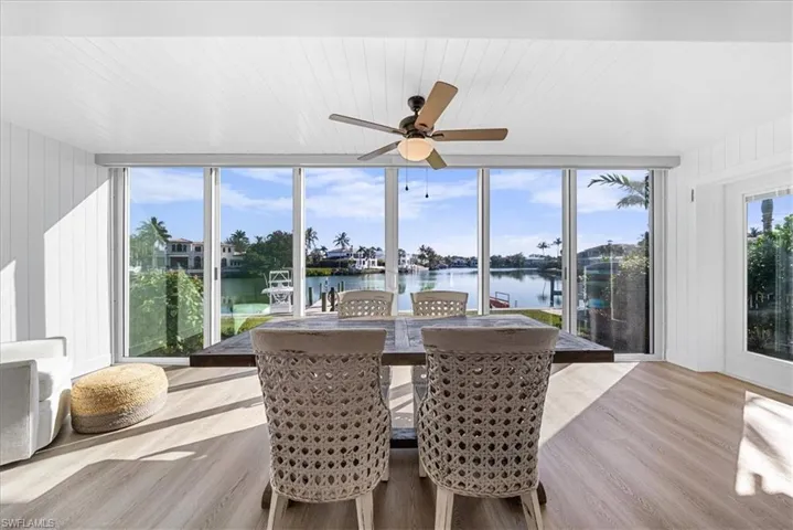 Sunroom with wood finished floors, wood walls, a water view, and expansive windows