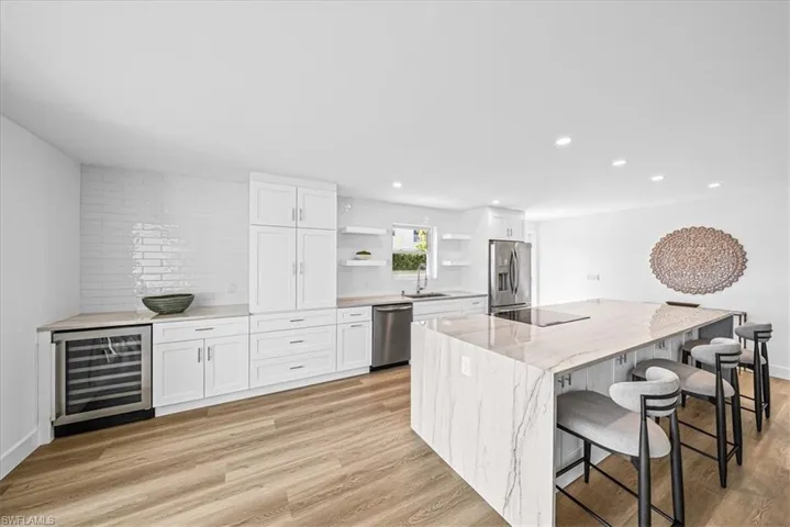 Kitchen with white cabinets, open shelves, a kitchen breakfast bar, light wood-type flooring, and wine cooler