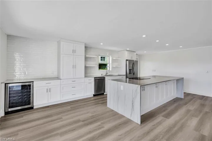 Kitchen featuring white cabinetry, wine cooler, open shelves, a spacious island, and light wood-style floors