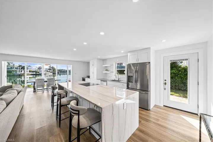 Kitchen with white cabinetry, a kitchen breakfast bar, stainless steel fridge with ice dispenser, light wood-style floors, and recessed lighting