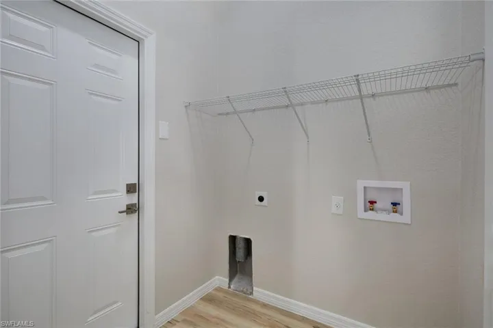 Laundry area featuring hookup for an electric dryer, hookup for a washing machine, light wood-type flooring, and baseboards