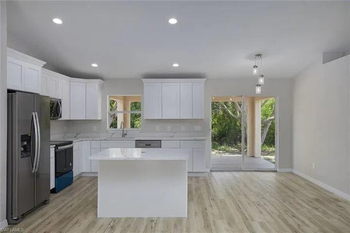 Kitchen with stainless steel appliances, healthy amount of natural light, white cabinetry, light wood-style flooring, and recessed lighting