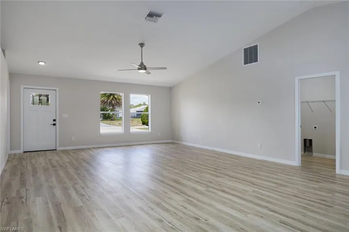 Unfurnished living room with lofted ceiling, ceiling fan, light wood-style flooring, baseboards, and recessed lighting
