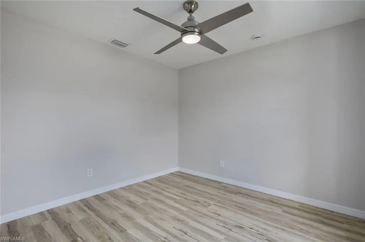 Empty room with light wood finished floors, ceiling fan, and baseboards