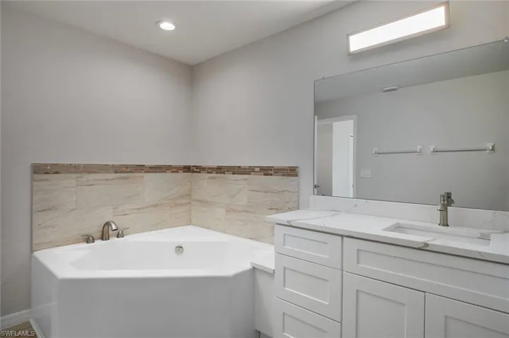 Full bath with vanity and a bath