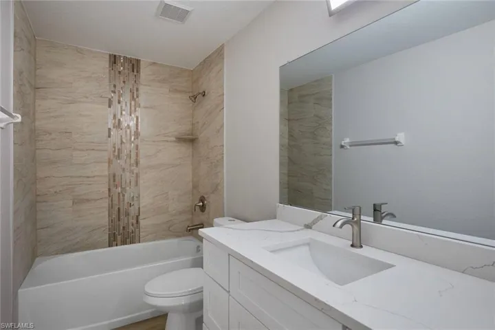 Bathroom featuring toilet, vanity, and washtub / shower combination