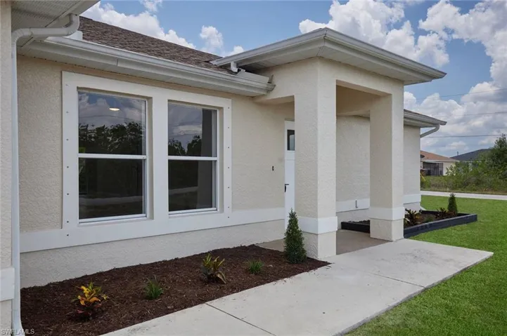 Entrance to property featuring stucco siding, a yard, and a patio area