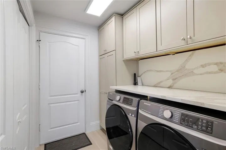 Laundry area with light hardwood / wood-style floors, cabinets, and washer and clothes dryer