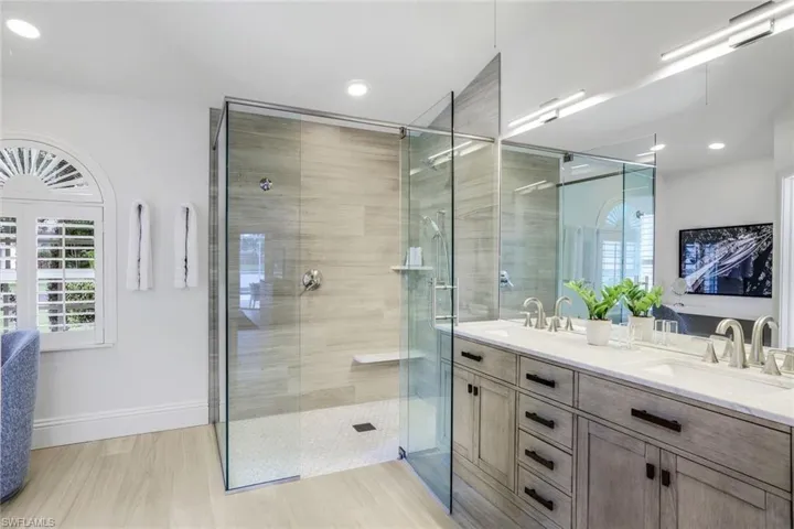 Bathroom featuring a shower with shower door and dual vanity
