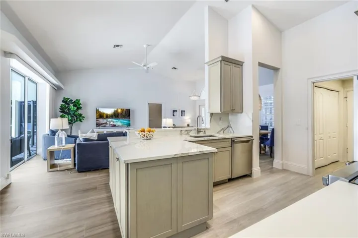 Kitchen with dishwasher, ceiling fan, light stone countertops, light wood-type flooring, and sink