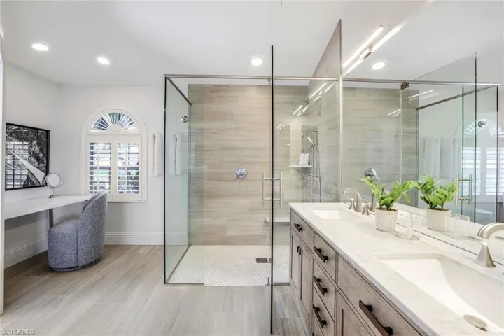 Bathroom featuring tile floors, walk in shower, vanity with extensive cabinet space, and double sink