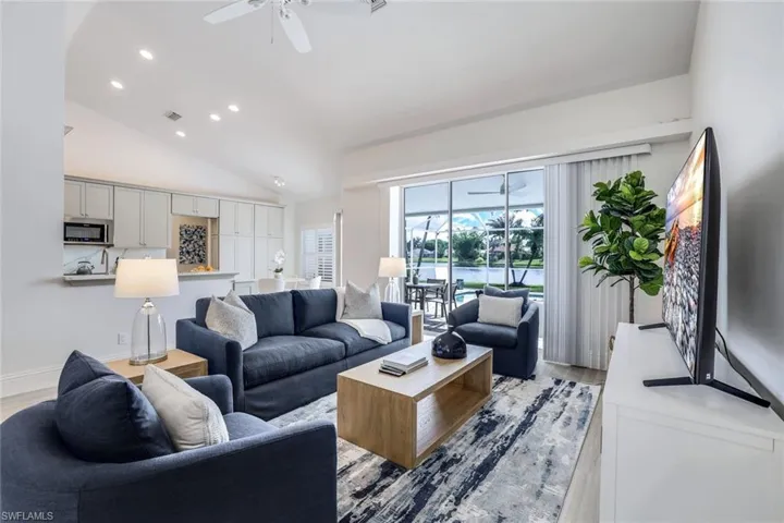 Living room with high vaulted ceiling, ceiling fan, and light hardwood / wood-style flooring