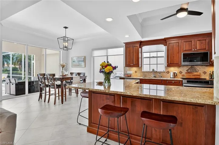 Custom Kitchen featuring cherry wood cabinets, crown molding, breakfast bar and light stone counters