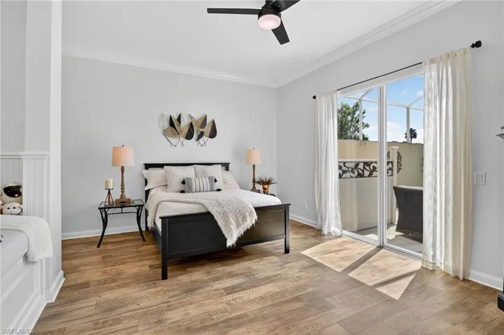 Bedroom featuring built in nook/bench seat, ornamental molding, wood finished floors, access to exterior, and ceiling fan