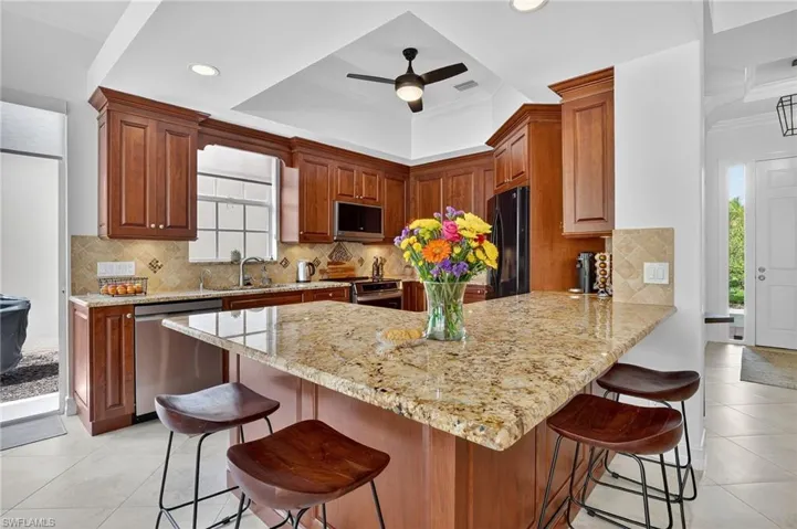 Kitchen with light tile patterned floors, a peninsula, plenty of natural light, a breakfast bar, and ornamental molding