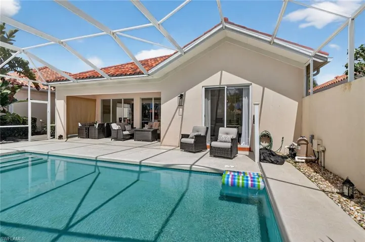 Back of home featuring pool, outdoor living space, patio area and sliders to the primary bedroom