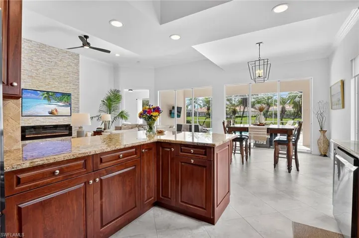 Kitchen with a peninsula, light stone countertops, crown molding, light tile patterned floors