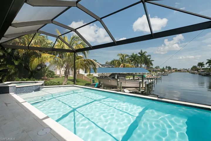 View of swimming pool with an in ground hot tub, a water view, a boat dock, and glass enclosure