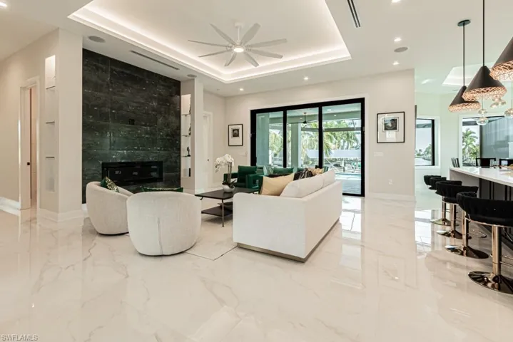 Living room featuring ceiling fan, a fireplace, and a tray ceiling