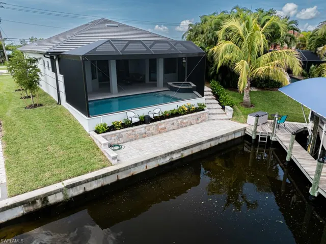 Back of property featuring a lanai, a patio area, a water view, and a lawn