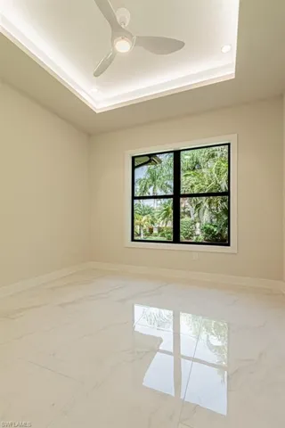 Spare room with ceiling fan, a tray ceiling, and a healthy amount of sunlight