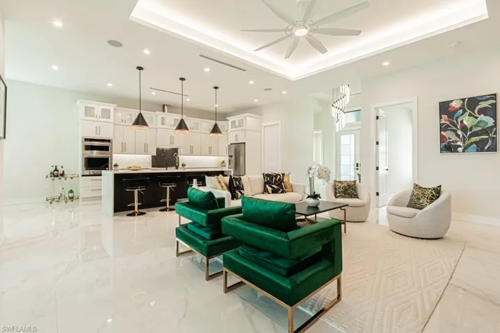 Living room with sink, ceiling fan, and a tray ceiling