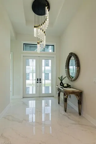 Entryway featuring a raised ceiling, a notable chandelier, and french doors