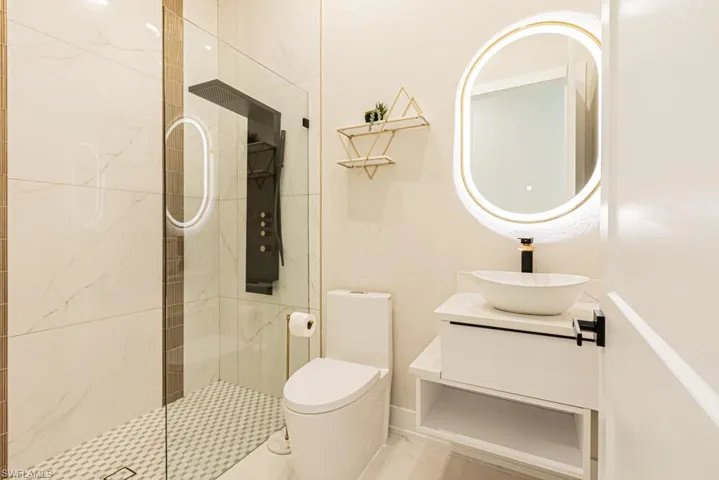 Bathroom featuring vanity, toilet, and a tile shower