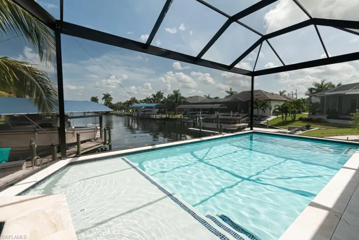 View of swimming pool featuring a water view, a boat dock, and glass enclosure