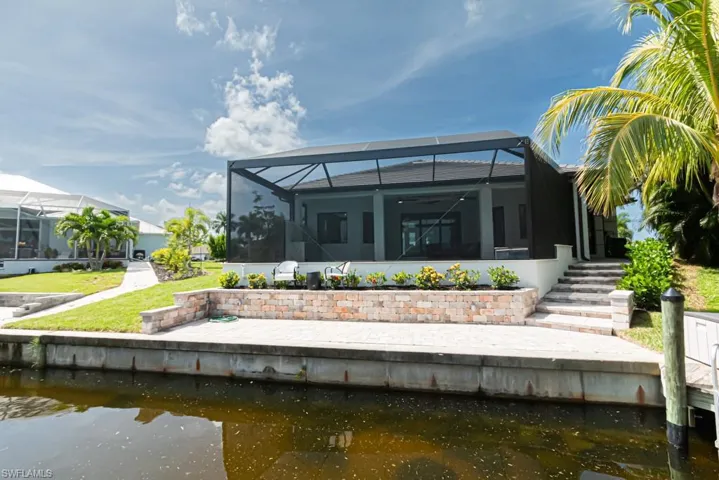 Rear view of house with a water view and glass enclosure