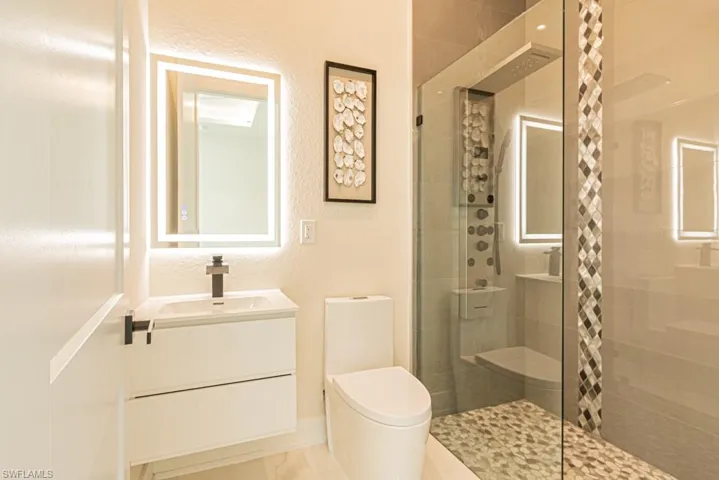 Bathroom featuring vanity, a shower with shower door, and toilet