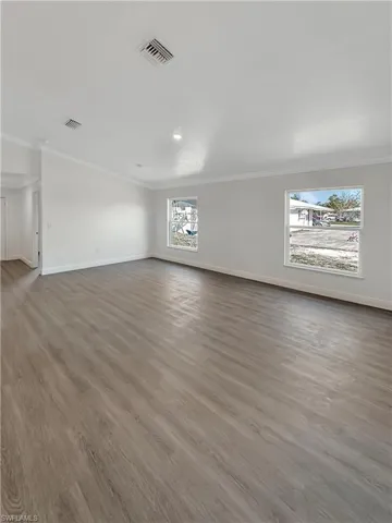 Spare room featuring dark wood-style floors and ornamental molding