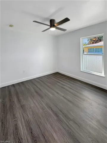 Unfurnished room with dark wood-style floors and ceiling fan