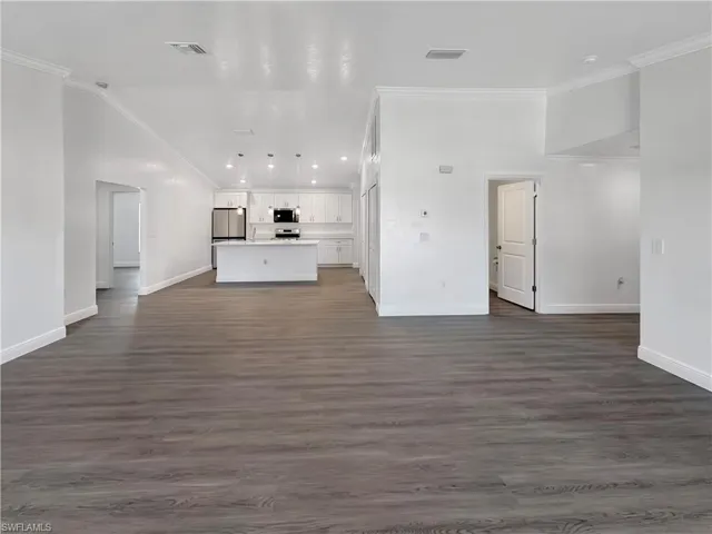 Unfurnished living room with crown molding, dark wood finished floors, and recessed lighting